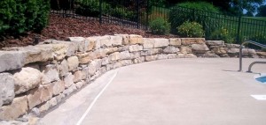 stone-wall-surrounding-pool-landscaping-and-hardscaping-around-swimming-pool